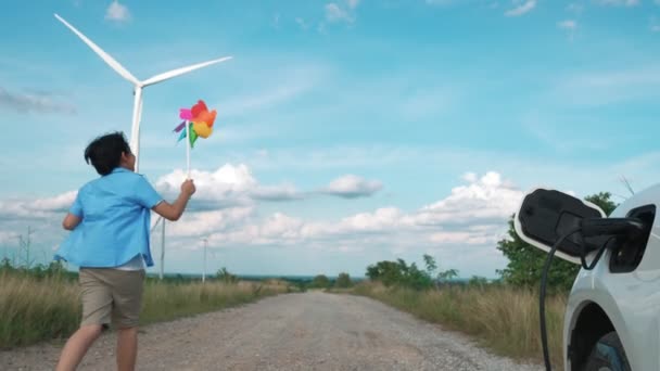 Postępowy Chłopiec Bawiący Się Wiatrak Obok Samochodu Farmie Turbin Wiatrowych — Wideo stockowe