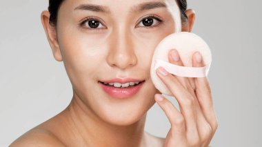 Closeup ardent woman applying her cheek with dry powder and looking at camera. Portrait of younger with perfect makeup and healthy skin concept.