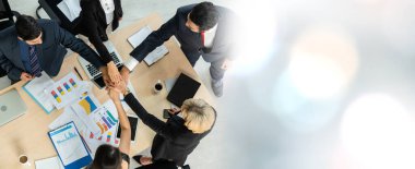 Mutlu iş adamları takım çalışmasının başarısını geniş görüşle kutlarken ofis masasındaki neşe yukarıdan çekiliyor. Genç işadamı ve işkadını işçiler neşeli bir zafer kazandılar. .