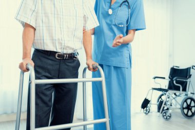 Physiotherapist assists her contented senior patient on folding walker. Recuperation for elderly, seniors care, nursing home.