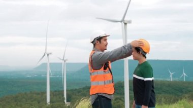 Oğluyla birlikte kırsal kesimdeki bir tepenin tepesinde ya da dağda bir rüzgar çiftliğinde mühendis. Yenilenebilir ve sürdürülebilir enerjinin gelecekteki üretimi için yenilikçi bir ideal. Rüzgar türbininden enerji üretimi.