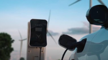 Çevreyi korumak için rüzgar türbininden yeşil ve yenilenebilir enerjiyle çalışan şarj istasyonunda şarj edilen gelişmiş gelecek enerji altyapısı konsepti.