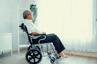 Portrait of an elderly man in a wheelchair alone with himself at home but contented with his lot in life. Convalescent facility for the crippled elderly in a nursing home.
