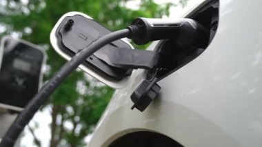 Yakın çekim yenilikçi modern ulaşım konsepti, elektrikli araba şarj istasyonunda gökyüzünden yansıyan yüksek detay ile şarj ediliyor. Yenilenebilir enerji tarafından kullanılan çevre dostu elektrikli araç.