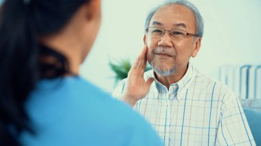 A young female doctor inquires about personal information of a contented senior at home. Medical care for the elderly, elderly illness, and nursing homes, home care.