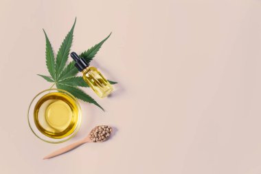 Şişede CBD yağı, damlacık kapağı, sativa yeşil kenevir ve kenevir tohumu bulunan yasallaştırılmış marihuana özellikleri. Copyspace ve reklam için esrar ürünü.