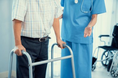 Physiotherapist assists her contented senior patient on folding walker. Recuperation for elderly, seniors care, nursing home.