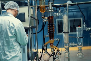 Bilim adamı ya da eczacı tıbbi ve sağlık hizmetleri için kenevir yağı çıkarıyor. Esrar ürünlerinden alınan sağlık hizmetleri eczanesi. Cam tüpler ve teçhizatlı kenevir yağı çıkarma makinesi.