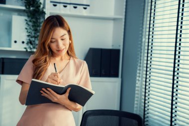 Young competent office lady, intern, secretary holding a log in office room. Concept of various career for office working. Concept of diverse office careers.