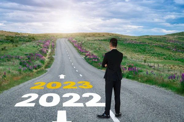 The 2023 New Year journey and future vision concept . Businessman traveling on highway road leading forward to happy new year celebration in beginning of 2021 for fresh and successful start .
