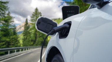 Elektrikli araç konsepti, yeşil çevre için yenilenebilir ve temiz enerjiyle çalışan EV otomobilinin varış noktasına ulaşmadan önce ormandaki şarj istasyonunun enerjisini şarj etmek için durur..