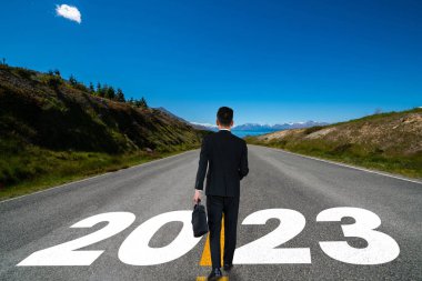 2023 yılbaşı yolculuğu ve gelecek vizyon konsepti. 2021 'in başında yeni ve başarılı bir başlangıç için mutlu bir yeni yıl kutlamasına giden otoyolda seyahat eden iş adamı. .
