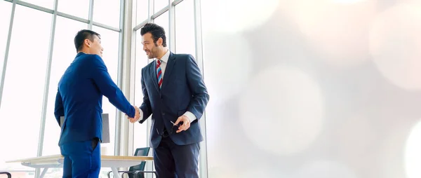 金融取引契約に関する専門的合意を示す観点から 営業所で握手をする事業者 — ストック写真