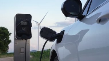 Çevreyi korumak için rüzgar türbininden yeşil ve yenilenebilir enerjiyle çalışan şarj istasyonunda şarj edilen gelişmiş gelecek enerji altyapısı konsepti.