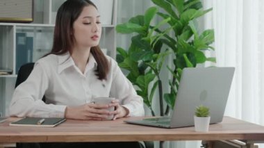 Ofiste çalışan ve dizüstü bilgisayar yazan hevesli bir iş kadını. Masasında oturmuş laptopla çalışan güzel bir ofis hanımı..