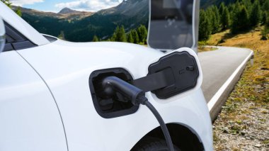 Tepe yolundaki şarj istasyonunda elektrikli arabanın çevresel farkındalığı için yenilikçi bir kavram. EV araba temiz çevre için yenilenebilir enerjiden güç alıyor.