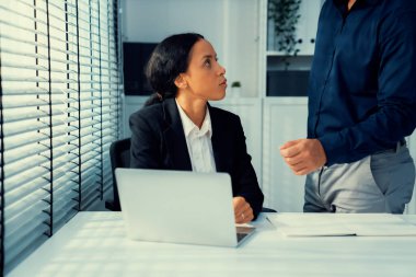 Competent female employee discussing with her colleague, employer using laptop at her office. Interpersonal relations among coworkers.