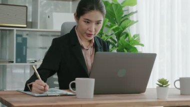Ofiste çalışan ve dizüstü bilgisayar yazan hevesli bir iş kadını. Masasında oturmuş laptopla çalışan güzel bir ofis hanımı..