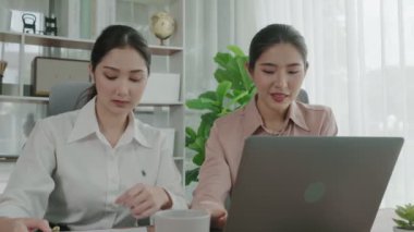 Ofis çalışma alanında birlikte çalışan iki genç hevesli iş kadını. Genç meslektaşlar tartışırken ve dizüstü bilgisayar kullanırken. Modern ofis çalışanları masada birlikte oturuyorlar..