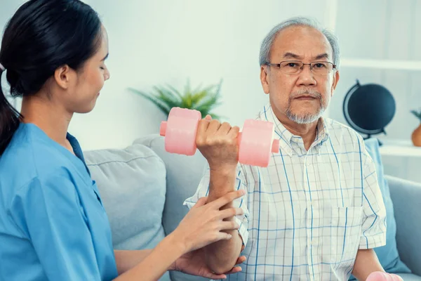 Unyielding senior patient doing physical therapy with the help of his caregiver. Senior physical therapy, physiotherapy treatment, nursing home for the elderly