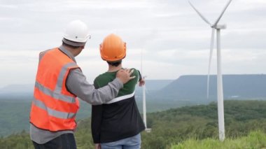 Oğluyla birlikte kırsal kesimdeki bir tepenin tepesinde ya da dağda bir rüzgar çiftliğinde mühendis. Yenilenebilir ve sürdürülebilir enerjinin gelecekteki üretimi için yenilikçi bir ideal. Rüzgar türbininden enerji üretimi.
