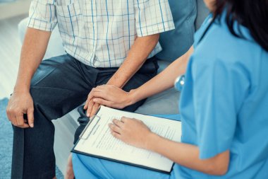 Senior man feeling contented as his caregiver provides him with good news about his health at medical consultation.