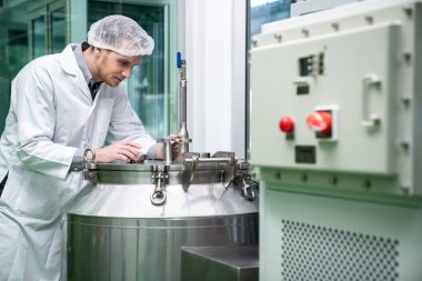 Bir bilim adamının portresi, eczacı laboratuarda bilimsel ekipman kullanarak kenevir yağı çıkarıyor. Alternatif tıbbi tedavi için esrar çıkarma kavramı