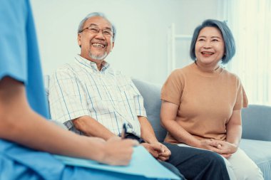 Female doctor visiting a contented elderly couple at their home. Health care, senior health support staff.