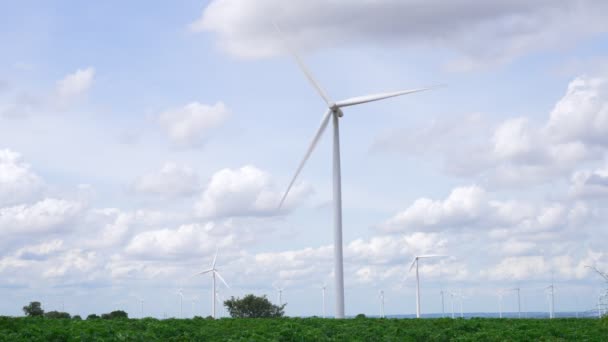 グリーンフィールドや丘の上に風力タービンファームによって現代の生活様式を電力する再生可能エネルギー源として風力を利用する進歩的な方法 風車発電機はCo2排出のない電気を発生させます — ストック動画