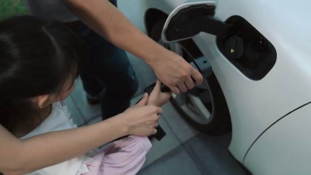 进步的父母在学校接女儿回来了 他们带着电动汽车和可再生能源的概念 在家里为电动汽车充电 替代生态交通 — 图库视频影像