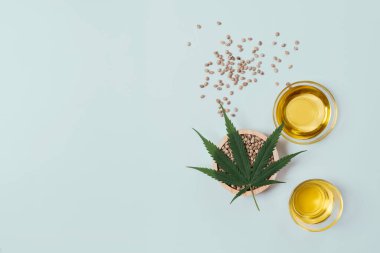 CBD yağı, cam kasede THC tintürü, damlalık kapaklı şişe ve boş arka planda kenevir yaprağı minimalizmle çevrili bir yığın kuru kenevir tohumu. Yasal marihuana konsepti.