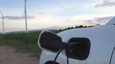 Çevreyi korumak için rüzgar türbininden yeşil ve yenilenebilir enerjiyle çalışan şarj istasyonunda şarj edilen gelişmiş gelecek enerji altyapısı konsepti.