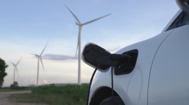Çevreyi korumak için rüzgar türbininden yeşil ve yenilenebilir enerjiyle çalışan şarj istasyonunda şarj edilen gelişmiş gelecek enerji altyapısı konsepti.