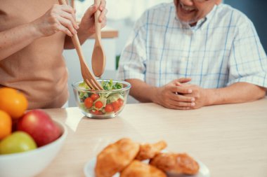 Contented senior couples who are happy to cook together with bread veggies and fruit in their kitchen.