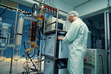 Bilim adamı ya da eczacı tıbbi ve sağlık hizmetleri için kenevir yağı çıkarıyor. Esrar ürünlerinden alınan sağlık hizmetleri eczanesi. Cam tüpler ve teçhizatlı kenevir yağı çıkarma makinesi.