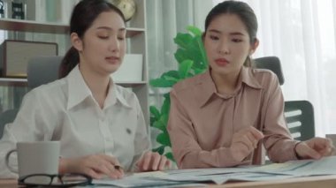 Ofis çalışma alanında birlikte çalışan iki genç hevesli iş kadını. Genç meslektaşlar tartışırken ve dizüstü bilgisayar kullanırken. Modern ofis çalışanları masada birlikte oturuyorlar..