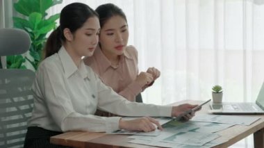 Ofis çalışma alanında birlikte çalışan iki genç hevesli iş kadını. Genç meslektaşlar tartışırken ve dizüstü bilgisayar kullanırken. Modern ofis çalışanları masada birlikte oturuyorlar..