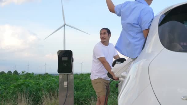 渐进式快乐家庭的概念 享受他们在风电场与电动汽车的时光 充电站风力涡轮机洁净可再生能源驱动的电动汽车 — 图库视频影像
