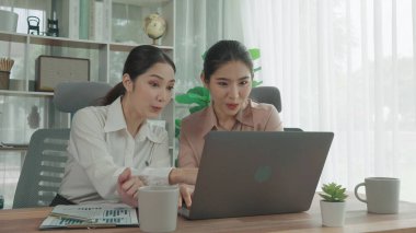 Ofis çalışma alanında birlikte çalışan iki genç hevesli iş kadını. Genç meslektaşlar tartışırken ve dizüstü bilgisayar kullanırken. Modern ofis çalışanları masada birlikte oturuyorlar..