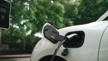 Yakın çekim yenilikçi modern ulaşım konsepti, elektrikli araba şarj istasyonunda gökyüzünden yansıyan yüksek detay ile şarj ediliyor. Yenilenebilir enerji tarafından kullanılan çevre dostu elektrikli araç.