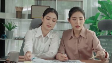 Ofis çalışma alanında birlikte çalışan iki genç hevesli iş kadını. Genç meslektaşlar tartışırken ve dizüstü bilgisayar kullanırken. Modern ofis çalışanları masada birlikte oturuyorlar..