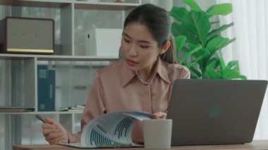 Ofiste çalışan ve dizüstü bilgisayar yazan hevesli bir iş kadını. Masasında oturmuş laptopla çalışan güzel bir ofis hanımı..