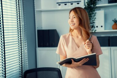 Young competent office lady, intern, secretary holding a log in office room. Concept of various career for office working. Concept of diverse office careers.