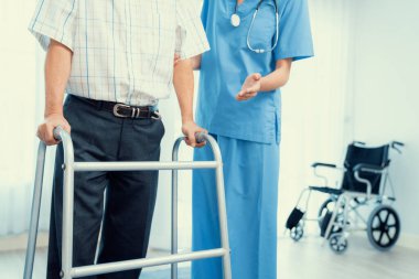 Physiotherapist assists her contented senior patient on folding walker. Recuperation for elderly, seniors care, nursing home.