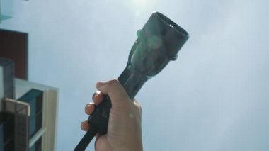 Yakın plan, çevresel kaygılar için alternatif sürdürülebilir temiz ve yeşil enerji kavramı olarak arka planda gün ortası gökyüzü ile elektrikli araç için bir EV kapsülü kavrıyor.