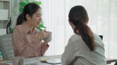 Ofis çalışma alanında birlikte çalışan iki genç hevesli iş kadını. Genç meslektaşlar tartışırken ve dizüstü bilgisayar kullanırken. Modern ofis çalışanları masada birlikte oturuyorlar..