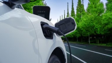 Elektrikli araç konsepti, yeşil çevre için yenilenebilir ve temiz enerjiyle çalışan EV otomobilinin varış noktasına ulaşmadan önce ormandaki şarj istasyonunun enerjisini şarj etmek için durur..