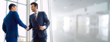 Business people handshake in corporate office in widen view showing professional agreement on a financial deal contract.
