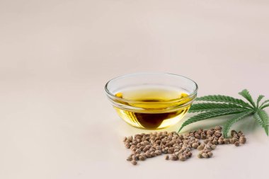 CBD yağı, cam kasede THC tintürü, damlalık kapaklı şişe ve boş arka planda kenevir yaprağı minimalizmle çevrili bir yığın kuru kenevir tohumu. Yasal marihuana konsepti.