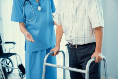 Physiotherapist assists her contented senior patient on folding walker. Recuperation for elderly, seniors care, nursing home.